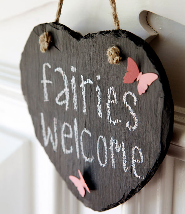 A wooden sign with the words: Fairies welcome written in white